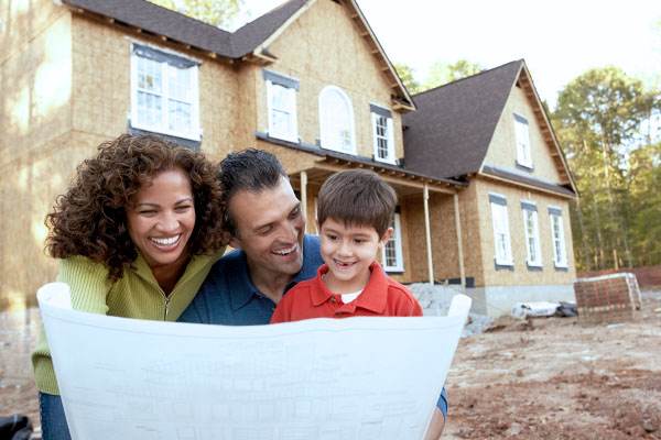 Couple with construction plans in front of home being built